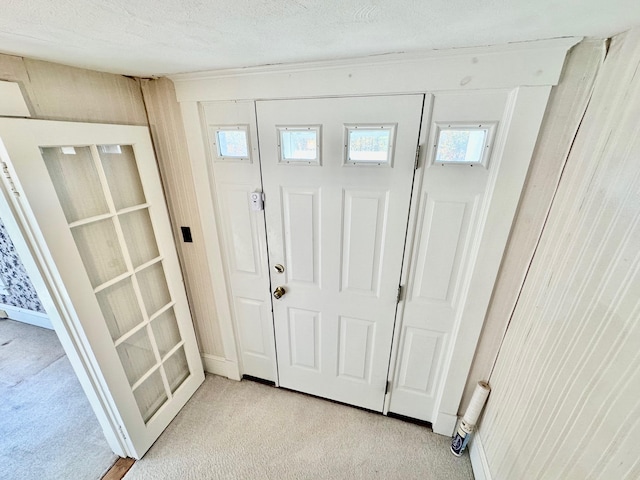 entryway with light carpet, a textured ceiling, and wooden walls