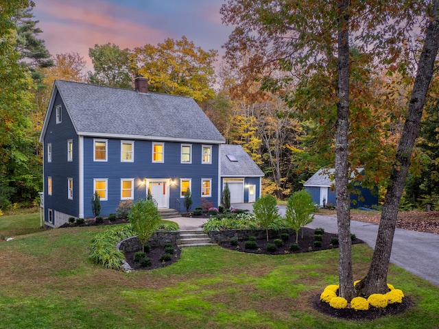 colonial-style house featuring a yard and a garage