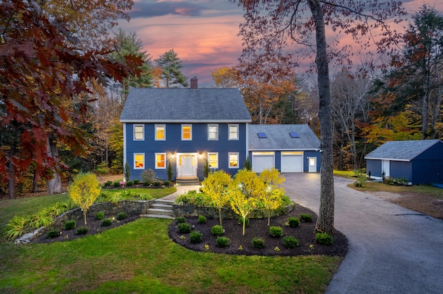 colonial inspired home featuring a lawn and a garage