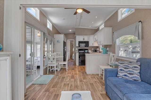 living area featuring a healthy amount of sunlight, ornamental molding, vaulted ceiling, and light wood finished floors