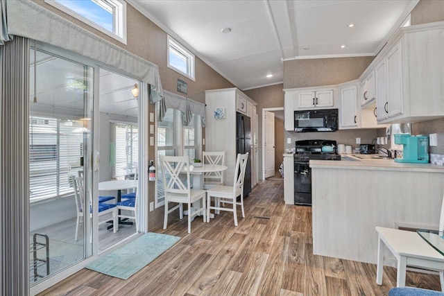 kitchen with black appliances, light hardwood / wood-style floors, white cabinetry, and a wealth of natural light