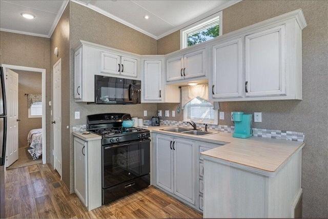 kitchen featuring white cabinets, black appliances, ornamental molding, hardwood / wood-style floors, and sink