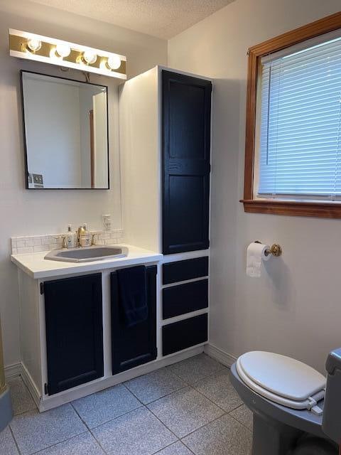 bathroom featuring a textured ceiling, vanity, and toilet