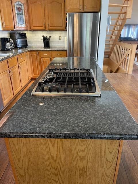 kitchen featuring appliances with stainless steel finishes, dark stone countertops, a center island, and tasteful backsplash