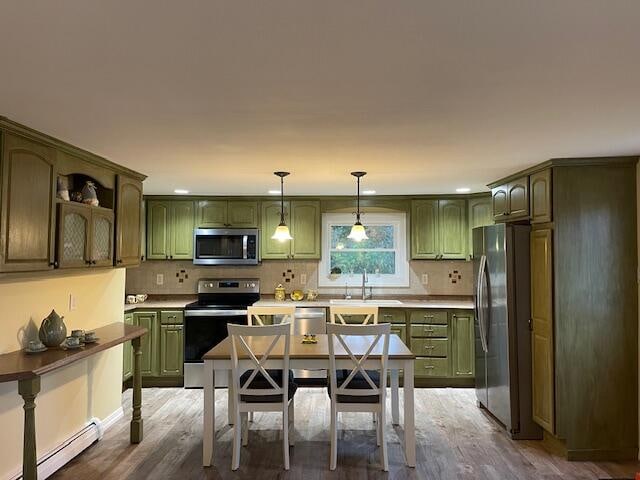 kitchen featuring a baseboard heating unit, wood-type flooring, hanging light fixtures, green cabinets, and appliances with stainless steel finishes