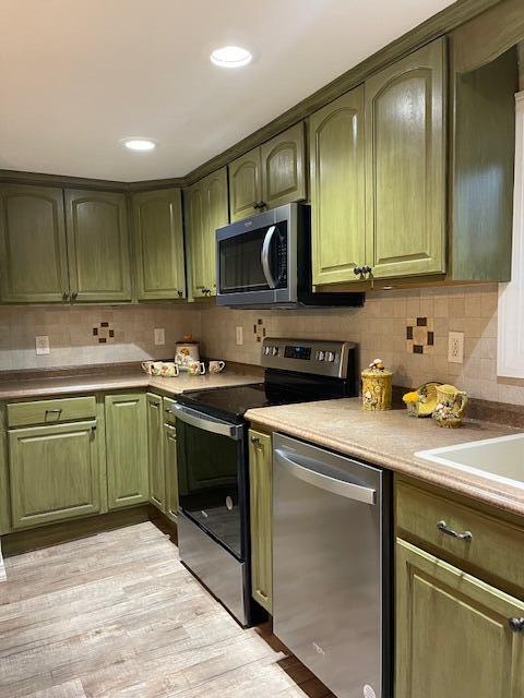 kitchen featuring appliances with stainless steel finishes, light wood-type flooring, and green cabinetry