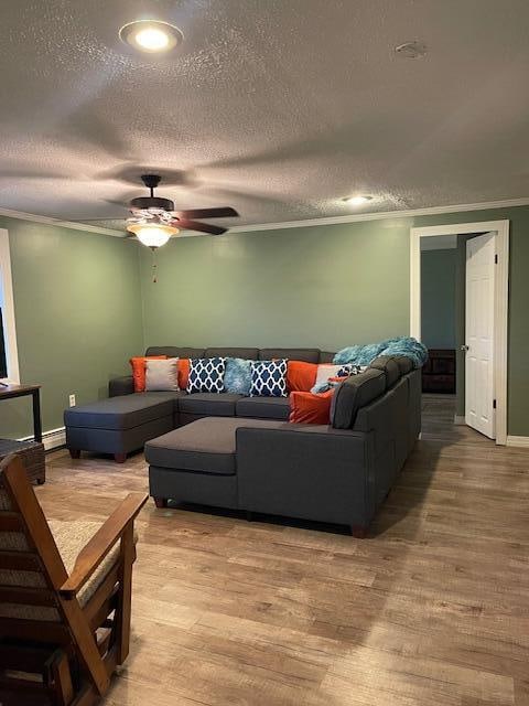 living room with ceiling fan, ornamental molding, a textured ceiling, and hardwood / wood-style floors