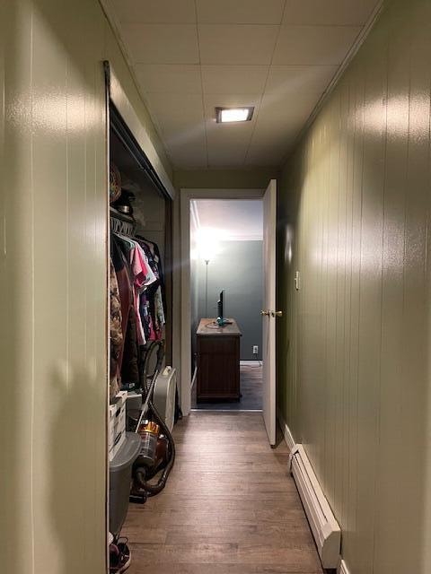 hallway with a baseboard radiator, wood walls, and hardwood / wood-style floors