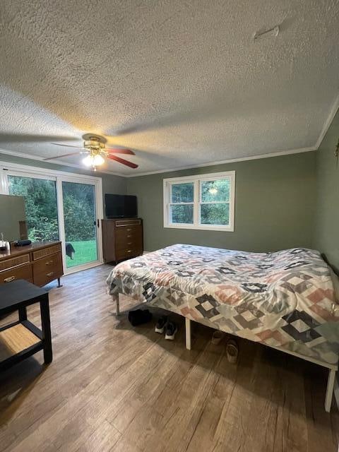 bedroom featuring ceiling fan, a textured ceiling, light hardwood / wood-style flooring, and crown molding