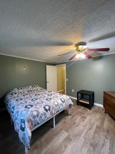 bedroom with ceiling fan, ornamental molding, a textured ceiling, and hardwood / wood-style floors