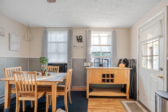 dining space with cooling unit, a textured ceiling, wood walls, and light hardwood / wood-style floors