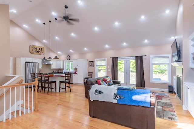 living room featuring high vaulted ceiling, light hardwood / wood-style floors, and ceiling fan