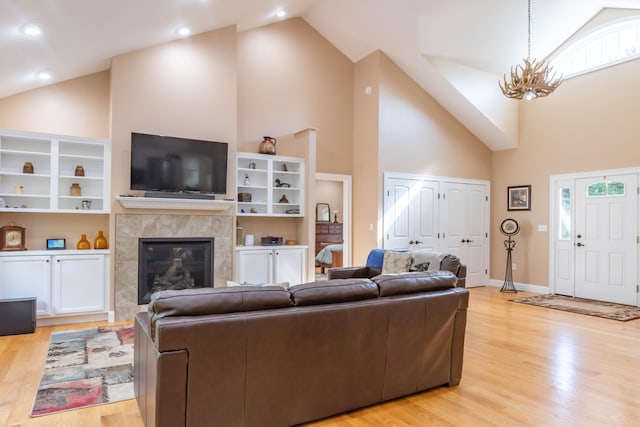 living room featuring a tiled fireplace, light hardwood / wood-style floors, high vaulted ceiling, and a wealth of natural light