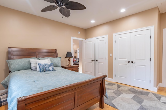 bedroom with light wood-type flooring, multiple closets, and ceiling fan