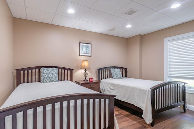 bedroom with a drop ceiling and dark wood-type flooring