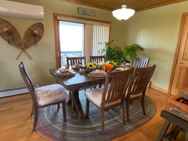 dining space featuring wood ceiling, an AC wall unit, light hardwood / wood-style flooring, ornamental molding, and a baseboard radiator