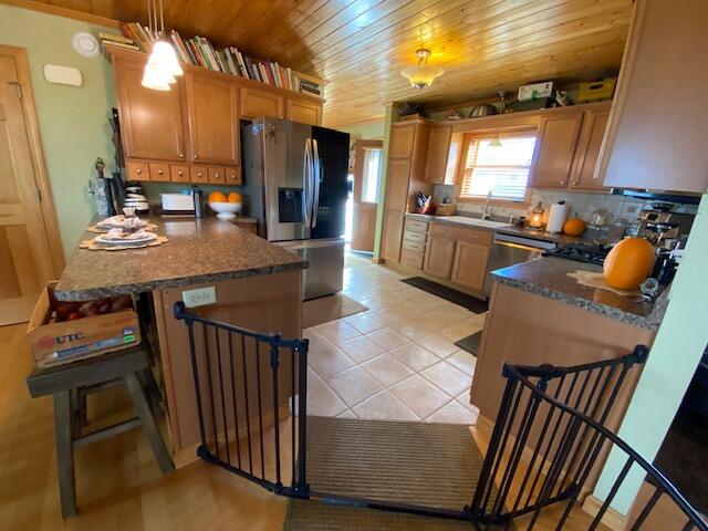 kitchen with pendant lighting, sink, appliances with stainless steel finishes, wooden ceiling, and a breakfast bar