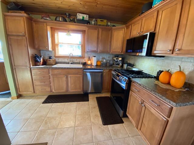 kitchen with tasteful backsplash, wooden ceiling, sink, appliances with stainless steel finishes, and light tile patterned floors