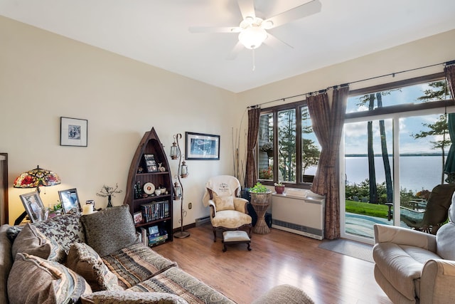 living room featuring wood-type flooring, a water view, and ceiling fan