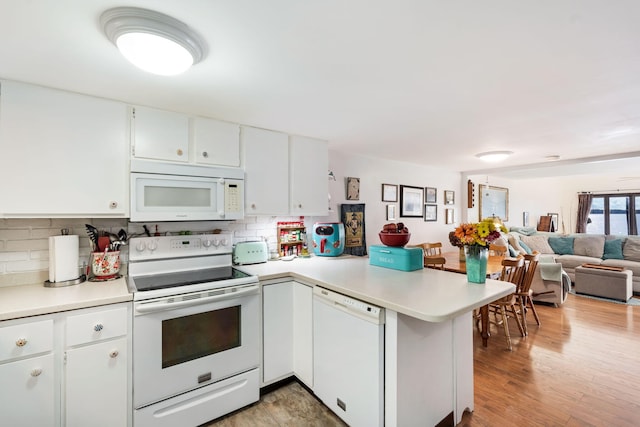 kitchen with kitchen peninsula, white appliances, light hardwood / wood-style floors, and white cabinetry