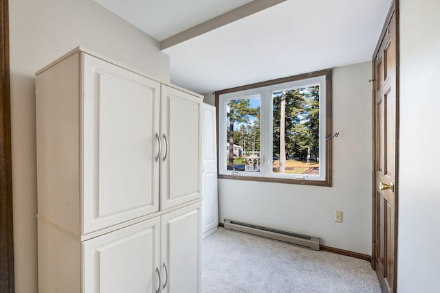 unfurnished bedroom with light colored carpet and a baseboard heating unit