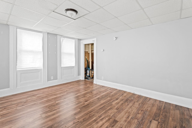 unfurnished room with wood-type flooring and a drop ceiling