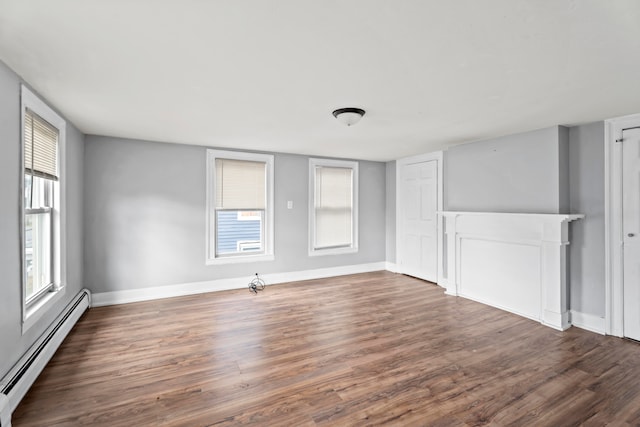 unfurnished room featuring a fireplace, dark wood-type flooring, and a baseboard heating unit