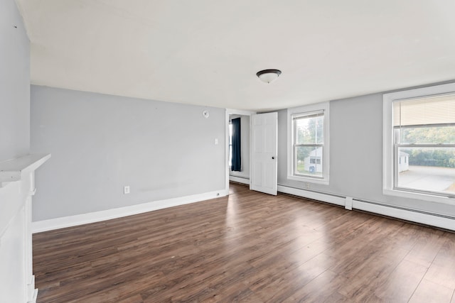 empty room featuring baseboard heating and dark wood-type flooring