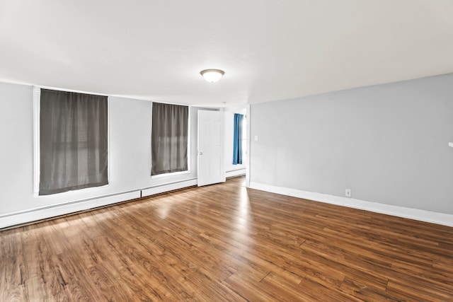 empty room featuring baseboard heating and hardwood / wood-style floors