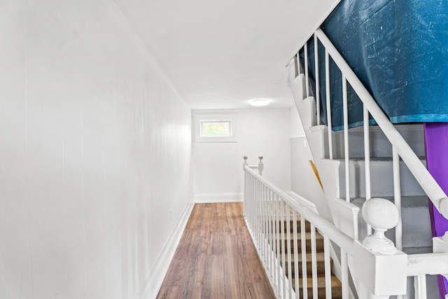 corridor with ornamental molding and hardwood / wood-style floors