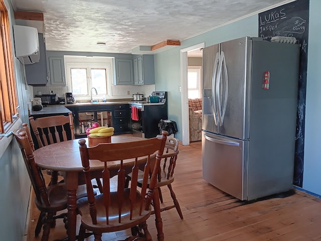 kitchen with backsplash, stainless steel fridge with ice dispenser, light wood-type flooring, gray cabinets, and a textured ceiling