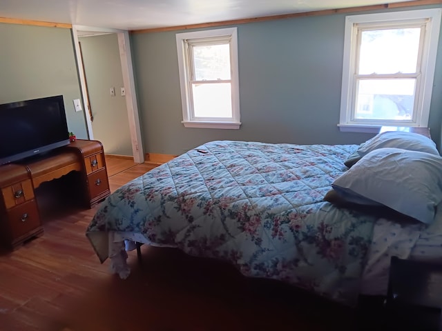 bedroom featuring built in desk, wood-type flooring, and multiple windows