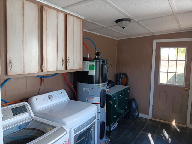 washroom with wood walls, hybrid water heater, separate washer and dryer, and cabinets