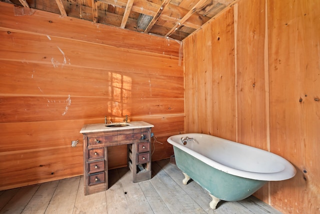 bathroom with hardwood / wood-style flooring, a bathtub, and wood walls