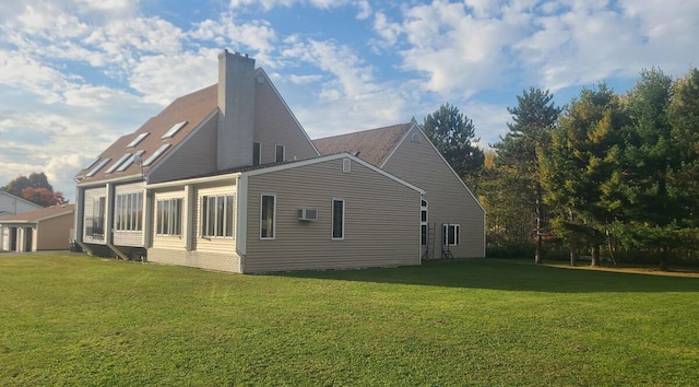 view of side of home with a wall mounted AC, a chimney, and a lawn