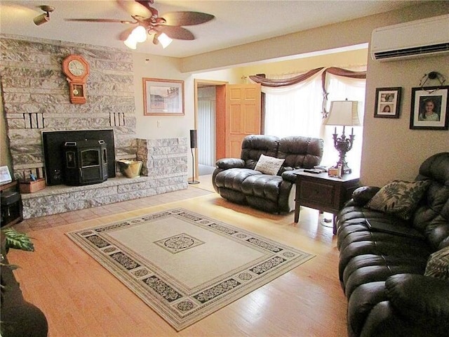 living area with wood finished floors, a wall unit AC, and ceiling fan