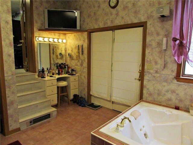 bathroom with wallpapered walls, vanity, a whirlpool tub, and tile patterned flooring