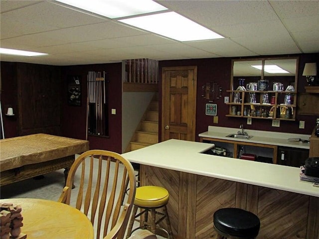 bar with stairway, a drop ceiling, a sink, and indoor bar