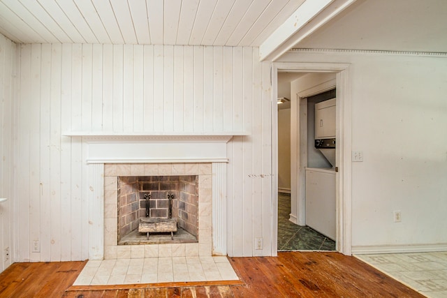 room details with a tiled fireplace, wood walls, and hardwood / wood-style floors