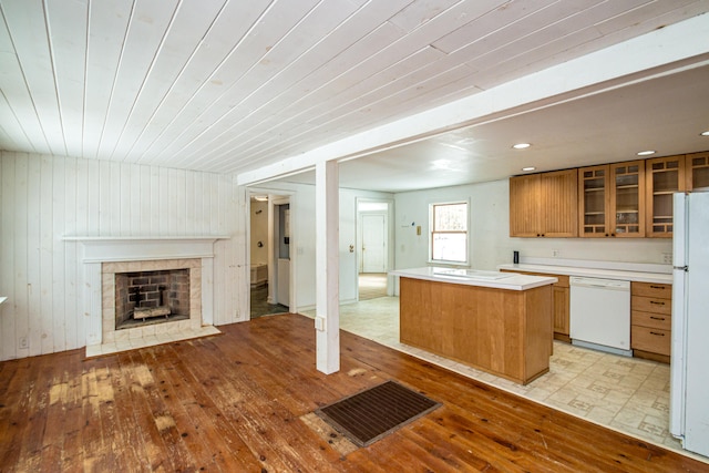 kitchen featuring a tile fireplace, wooden ceiling, light hardwood / wood-style floors, white appliances, and a kitchen island