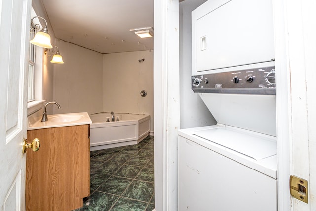 clothes washing area featuring stacked washer / dryer and sink