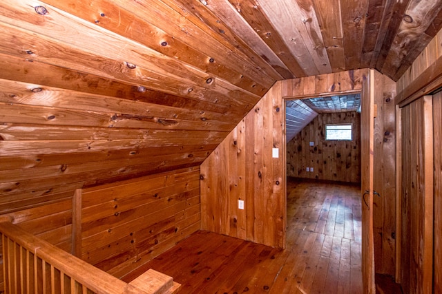 additional living space with wood walls, hardwood / wood-style floors, and lofted ceiling