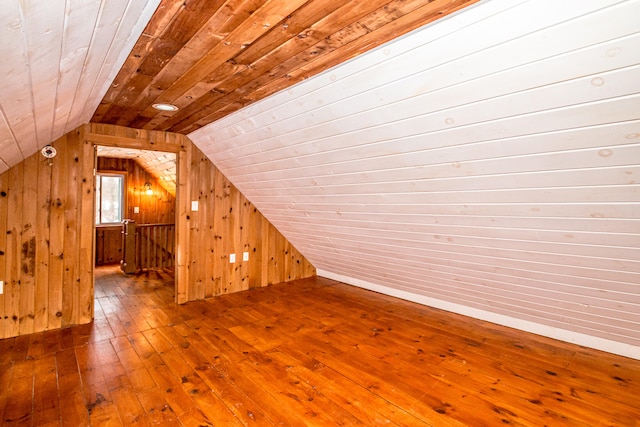 bonus room with wood-type flooring, vaulted ceiling, and wood walls