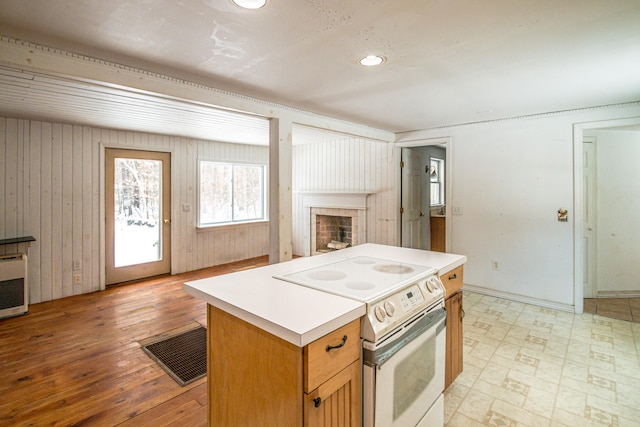 kitchen featuring wooden walls, light hardwood / wood-style flooring, white range with electric stovetop, a kitchen island, and heating unit