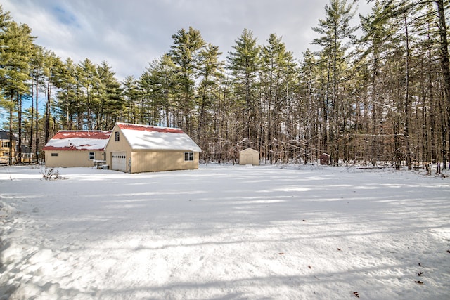 yard layered in snow with a garage and an outdoor structure