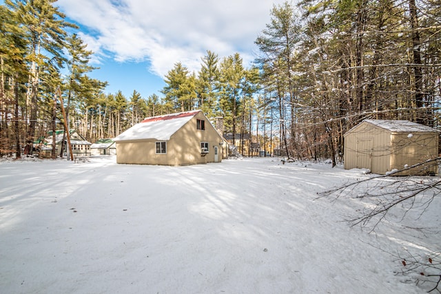 snowy yard with a storage shed