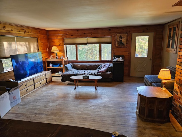 living room with wood-type flooring, wood walls, and a healthy amount of sunlight