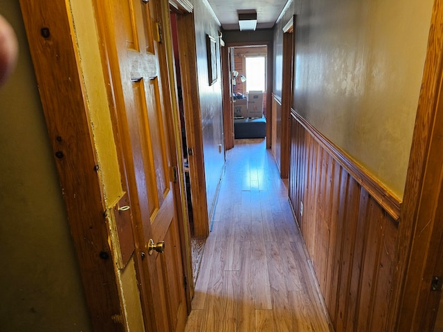 hall featuring light wood-type flooring and wood walls