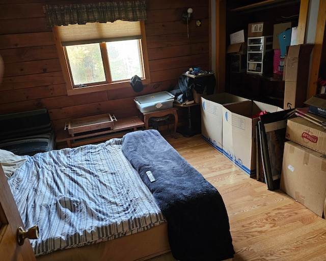 bedroom with wooden walls and light hardwood / wood-style floors