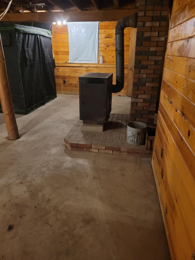 basement featuring wood walls and a wood stove